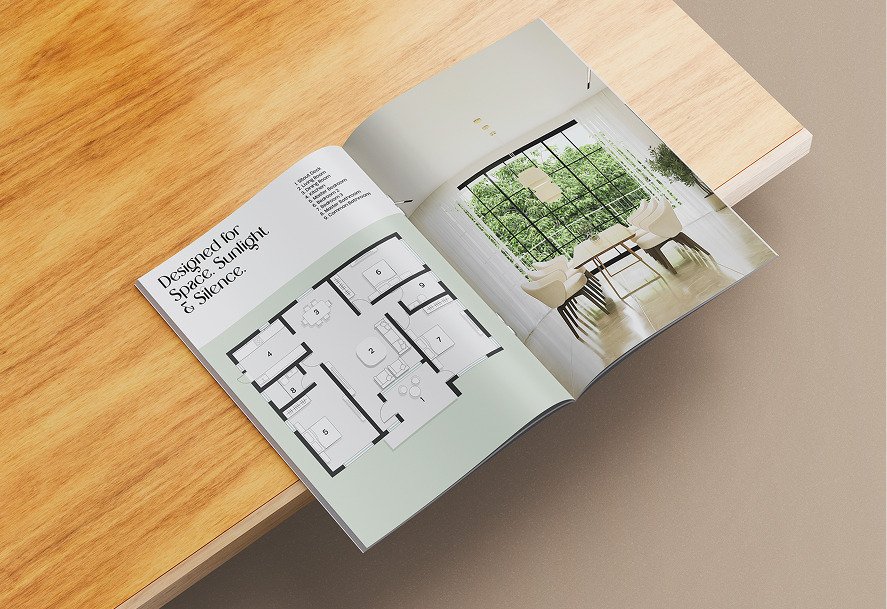 The folded brochure on a wooden surface, open to a floor plan in green linework