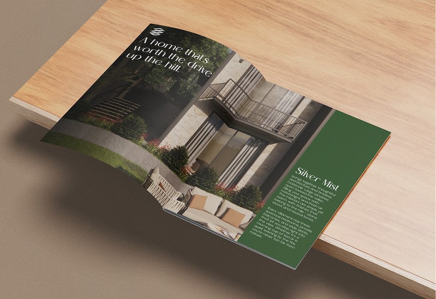 The folded brochure on a wooden surface, open to interior photography